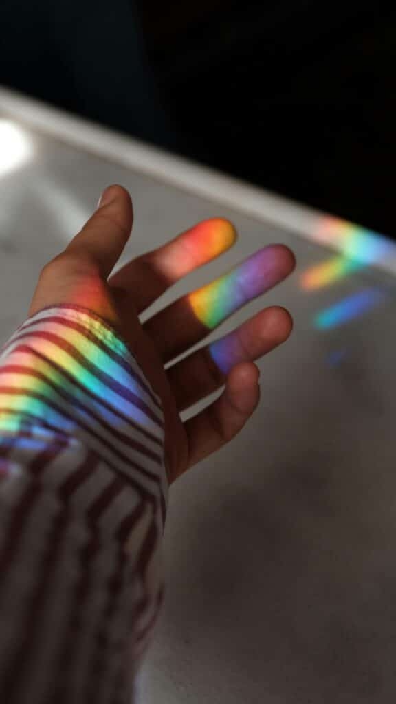 een hand met regenboog reflectie 